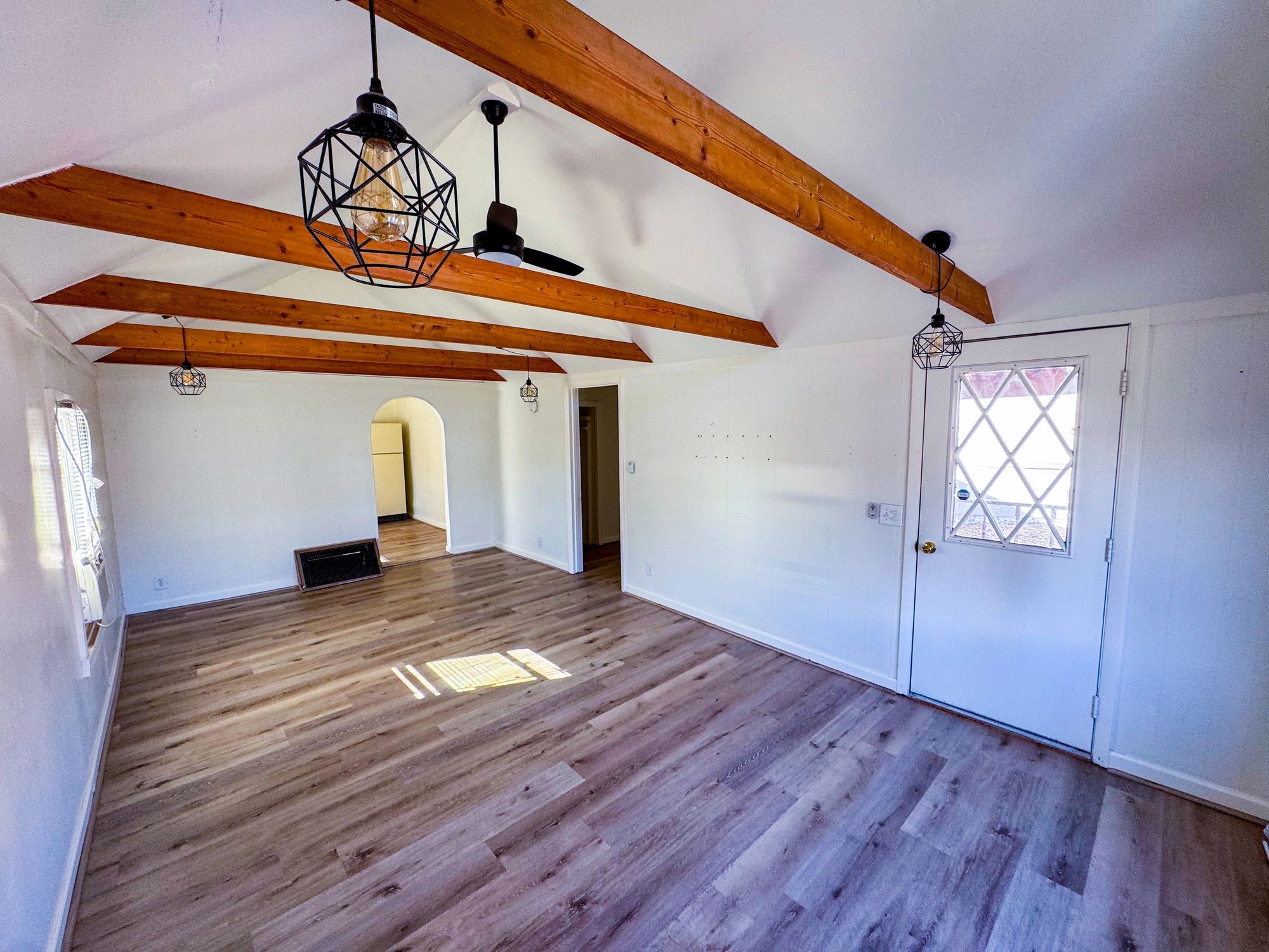 Expanded living room with exposed beams and natural light
