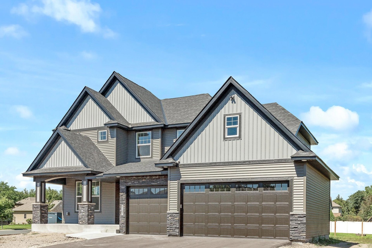 Two-story custom home with gray siding, stone accents and attached garage